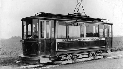 Im Jahr 1901 fährt eine Straßenbahn mit der Aufschrift "Bochum Gelsenkirchener Straßenbahnen" an einem Feld entlang