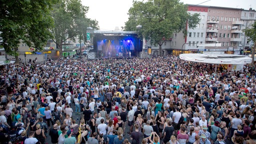 Eine Menschenmenge in der Innenstadt vor einer Musikbühne.