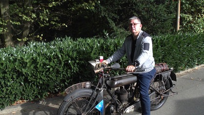 Stephan Homberger sitzt auf einem 100 Jahre alten Motorrad der Marke NSU