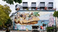 Ein ehemaliger Bunker, jetzt bunt bemalt und mit Wohnungen in den fünf Kuben, steht an einer befahrenen Straße in Düsseldorf-Bilk.