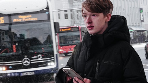 Der Bielefelder Bus-Spotter steht mit seinem Handy am Busbahnhof