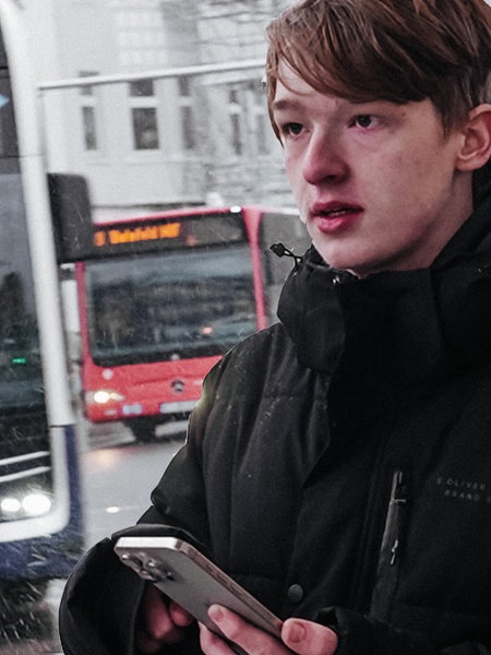 Der Bielefelder Bus-Spotter steht mit seinem Handy am Busbahnhof