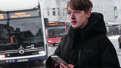 Der Bielefelder Bus-Spotter steht mit seinem Handy am Busbahnhof
