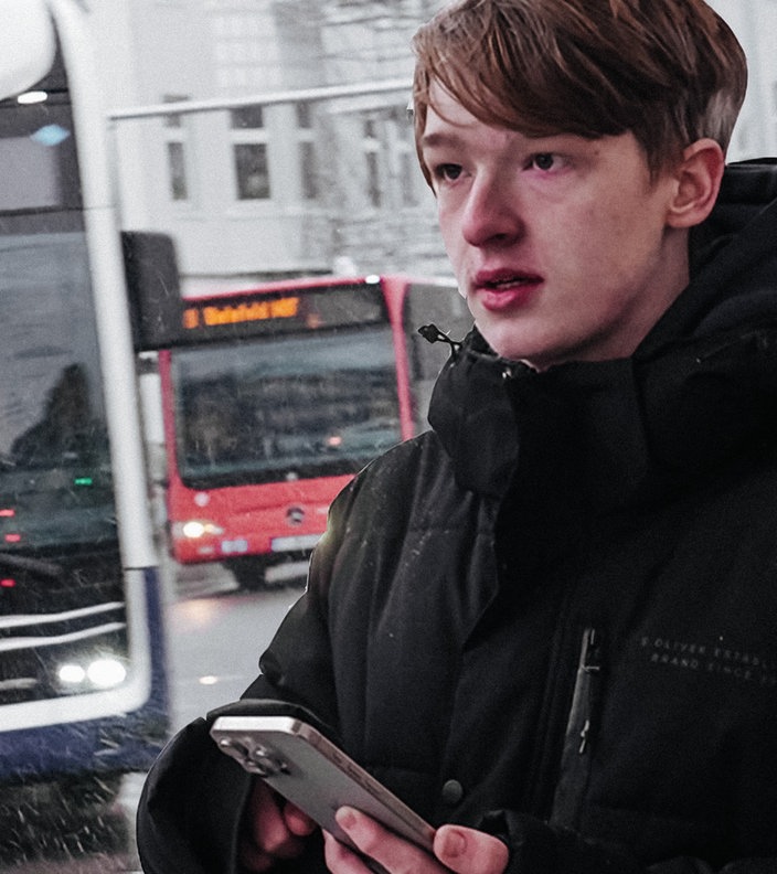 Der Bielefelder Bus-Spotter steht mit seinem Handy am Busbahnhof
