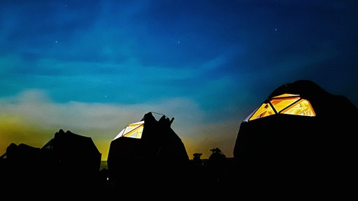 Vier Sternkuppelzelte stehen bei Nacht unter freiem Himmel.