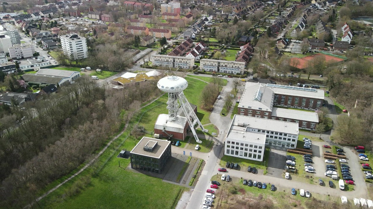 Man sieht das "Colani Ei" in Lünen, das in einem Industriegebiet steht. Es sind einige Autos und Gebäude drum herum zu sehen. 
