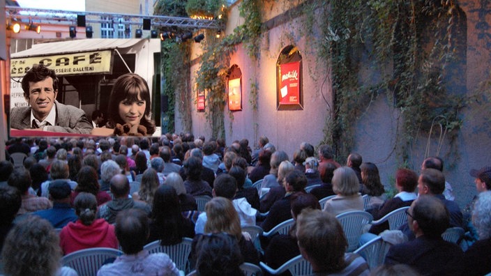 Zuschauer schauen auf eine Leinwand, auf der gerade ein Retro-Film läuft. Das Talflimmern-Kino ist in einer Häuserschlucht hinter der Alten Feuerwache