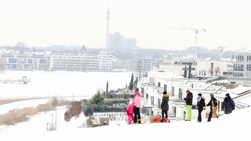 Blick von einem Hügel über einen verschneiten See, im Hintergrund die Skyline von Dortmund