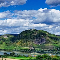 Blick über den Rhein auf grüne Hügel des Siebengebirges, samt Drachenburg und Drachenfels