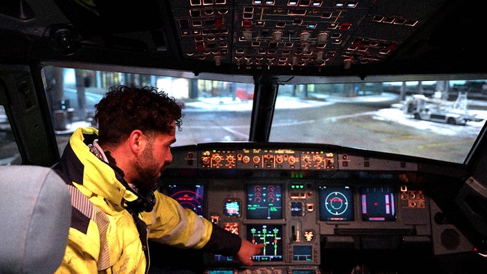 Fluggerätmechaniker Adam sitzt im Cockpit eines Flugzeugs und überprüft die Technik