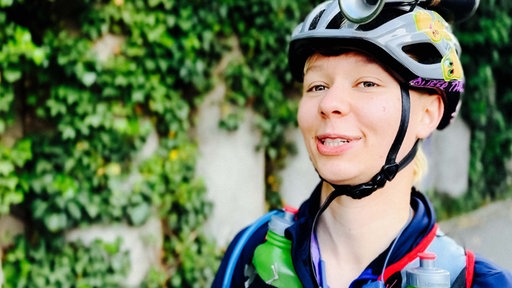 Eine Frau in Sportklamotten und mit einem Helm mit Hupe