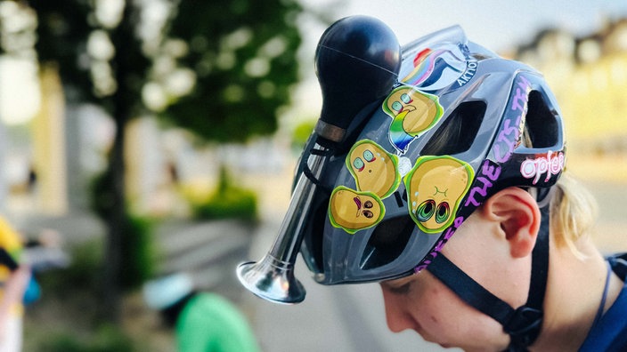 Eine Frau trägt einen Fahrradhelm, auf dem eine Tröte befestigt ist