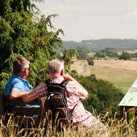 Ausblick vom Kalvarienberg auf dem Wanderweg "Eifelspur Toskana". Zwei Männer sitzen auf einer Bank und schauen in die Ferne.