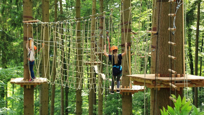 Zwei Kinder klettern in einem Hochseilgarten