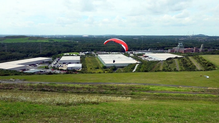 Ein Paraglider segelt über die Halde Hoheward.