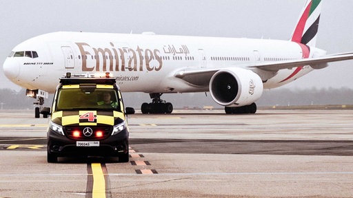 David Schönemann am Steuer des Follow-Me-Cars, im Hintergrund ein großes Flugzeug