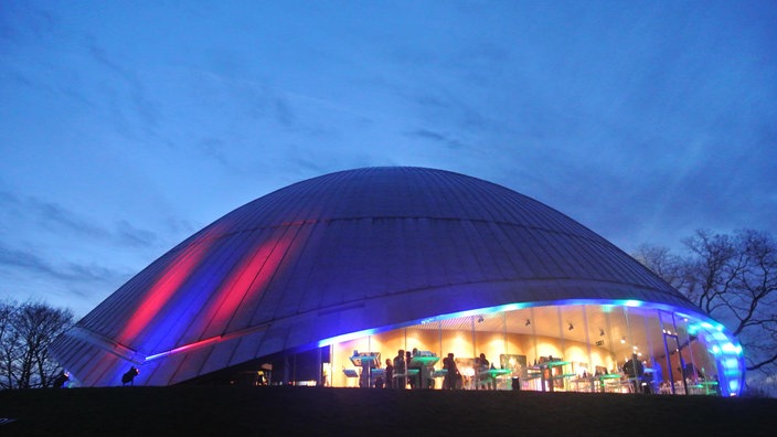 Die bunt beleuchtete Kuppel des Bochumer Planetariums von außen am Abend