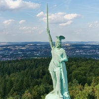 Die Statue des Hermannsdenkmals mit erhobenem Schwert, im Hintergrund die Stadt Detmold