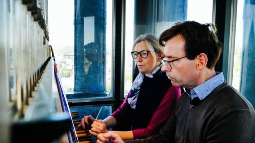 Eine Frau und ein Mann spielen das Carillon im Aachener Rathausturm.