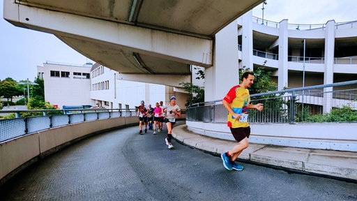 Mehrere Läufer joggen eine Parkhausauffahrt hoch.