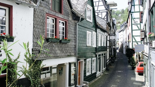 Eine Gasse windet sich zwischen Fachwerkhäusern hindurch.