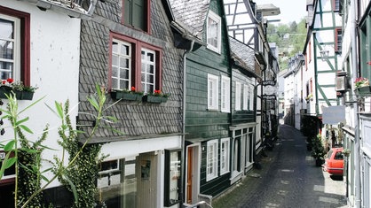 Eine Gasse windet sich zwischen Fachwerkhäusern hindurch.