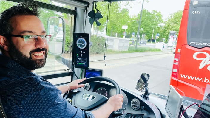 Abdulrahman Najjar, ein Mann mittleren Alters mit Brille, dunklen Haaren und Bart, sitzt am Steuer eines Busses.