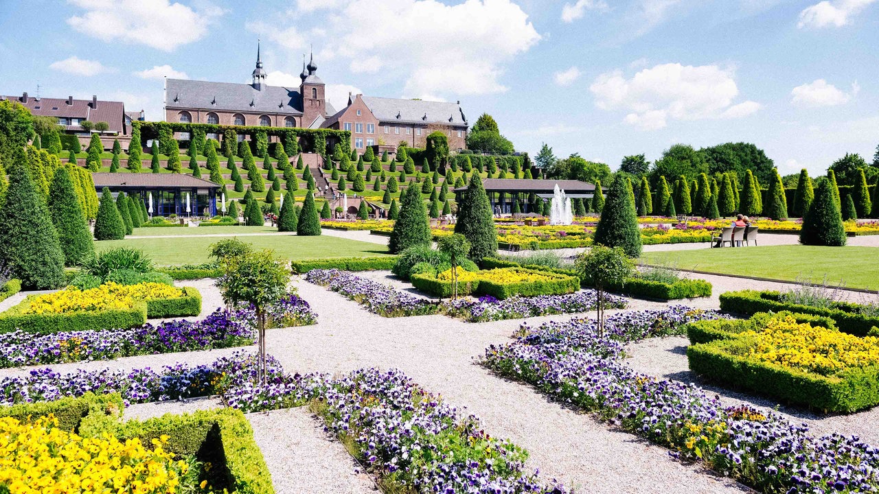Bunt bepflanzte Beete mit der Kloster Kamp im Hintergund.