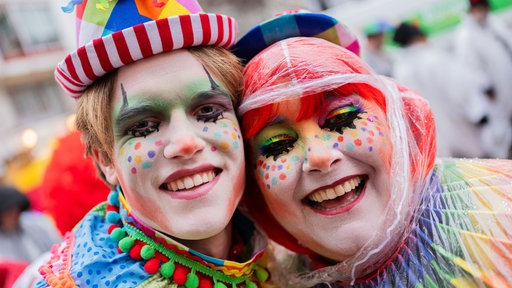 Mutter und Sohn tragen ein buntes und farbenfrohes Kostüm mit Kopfbedeckung und viel Schminke im Gesicht.
