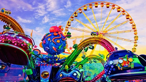 Froschperspektive in der Szenerie der Palmkirmes von einem Fahrgeschäft auf das Riesenrad am Horizont
