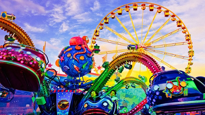 Froschperspektive in der Szenerie der Palmkirmes von einem Fahrgeschäft auf das Riesenrad am Horizont