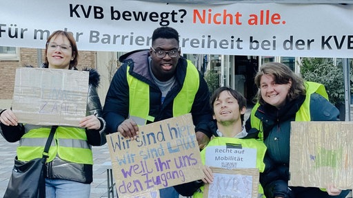Vier Demonstranten mit gelben Warnwesten und Schildern
