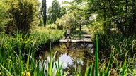 Eine Frau läuft über Steine auf einer Wasserfläche im MüGa-Park.