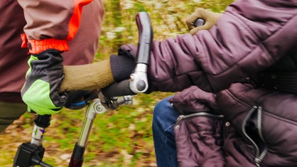 Zwei Menschen halten auf dem Tandem ihre Hände fest.