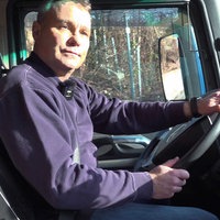 Alexander Herpich mit blauem Pullover, sitz auf dem Fahrersitz eines Lkws und hält das Lenkrad mit beiden Händen fest