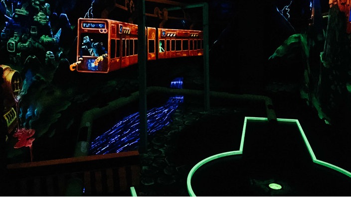 Links ein Modell der Schwebebahn, rechts ein grün umrandeter Minigolf-Parcours