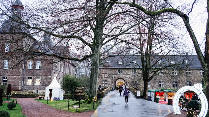 Die Brücke zu Schloss Hugenpoet, im Hintergrund das Schloss. Neben der Brücke stehen Markthütten.