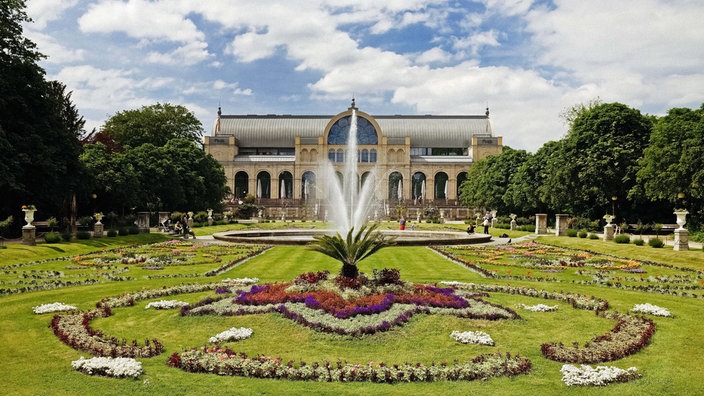 Die Flora in Köln, davor ein Park mit Springbrunnen