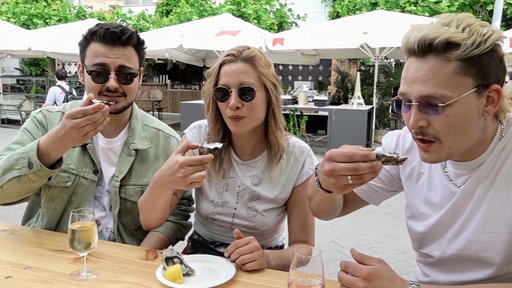 Drei junge Menschen essen Austern.