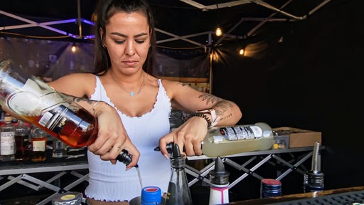Eine Barkeeperin mixt einen Cocktail.