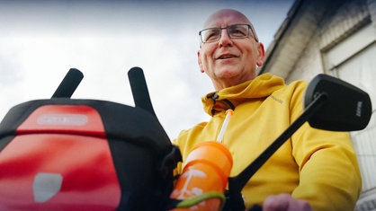 Thomas Fischer steht in einer gelben Jacke hinter dem Lenker seines voll bepackten Fahrrads