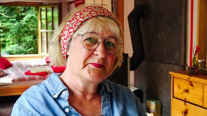 Petra Deutsch sitzt in dem Pilger-Bauwagen auf ihrem Grundstück