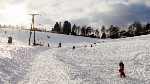 Erwachsene und Kinder mit Schlitten in der Elfringhauser Schweiz.
