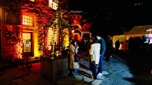Menschen stehen im beleuchteten Innenhof eines Schlosses 