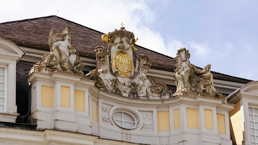 Außenfassade des Schlosses Augustusburg, gelb-beige Steine mit goldener Verzierung und Löwen-Statuen
