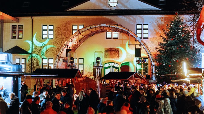 Weihnachtsmarkt in Innenhof von Schloss Benkhausen mit illuminiertem Schloss im Hintergrund