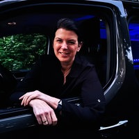 Kerstin Schulz-Höfel sitzt in ihrem schwarzen Bulli, den sie zu einem Party-Shuttle umfunktioniert hat. Im Inneren des Autos sind blaue LED- Lichter.