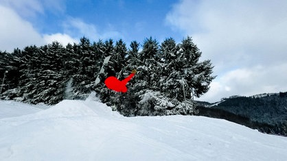 Skipiste darüber ein Skilift und dahinter Häuser. Alles ist mit dichtem Schnee bedeckt.