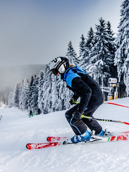 Skifahrer fahren in Winterberg eine schneebedeckte Piste hinunter.