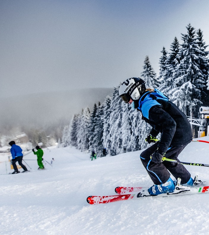 Skifahrer fahren in Winterberg eine schneebedeckte Piste hinunter.